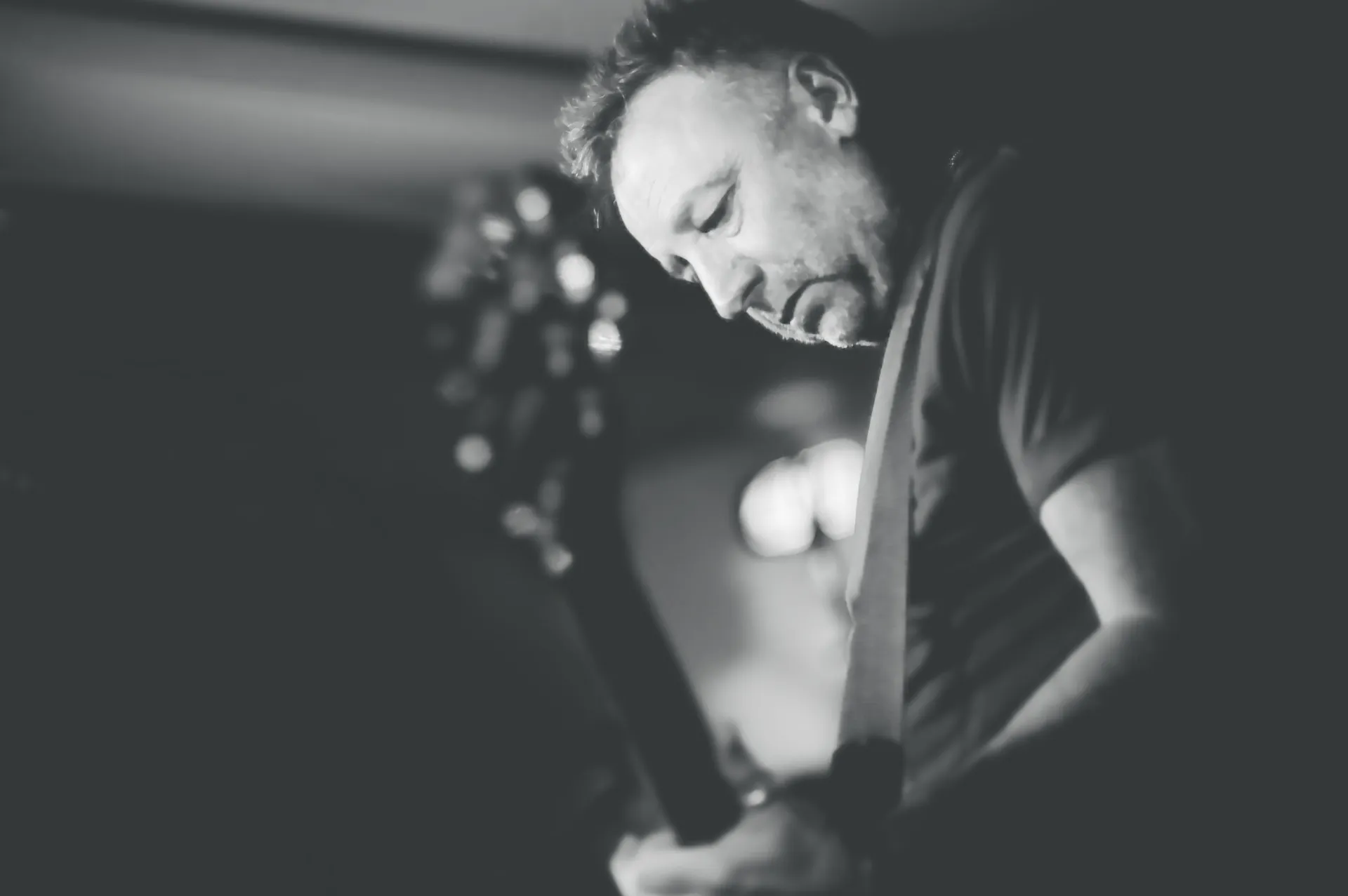 black and white photo of Peter Hook playing guitar photo credit Mark McNulty